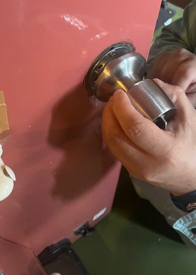 硬くなった玄関ドアノブを取り外し、新しい部品へ交換する作業風景（大阪市平野区）