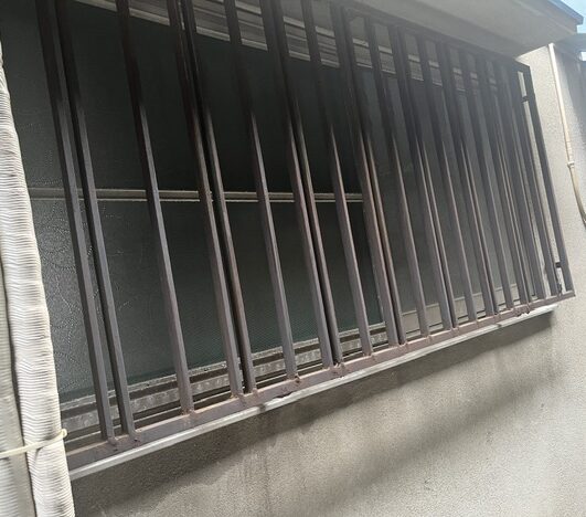 鉄柵の錆を落とし、油性塗料で下塗り・上塗りを行う作業スタッフの様子（大阪市平野区）