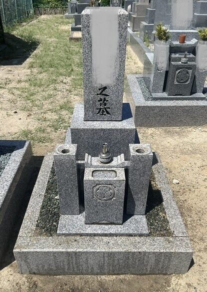 墓石を専用ブラシで磨き、周辺を清掃している作業スタッフの様子（大阪市平野区）